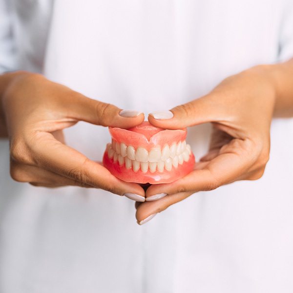 Dental team member holding dentures in manicured hands