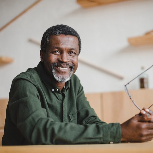 Man sitting and smiling while holding glasses